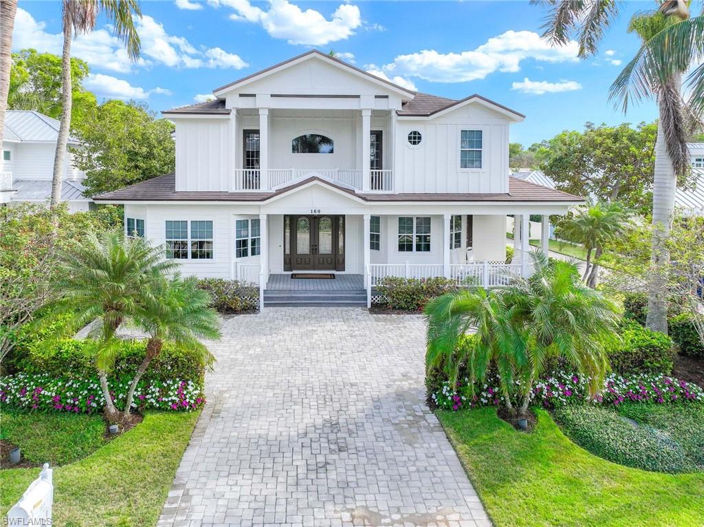 View of front facade featuring board and batten siding, french doors, a porch, a balcony, and decorative driveway