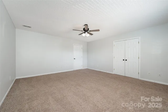 an empty room with windows and fan
