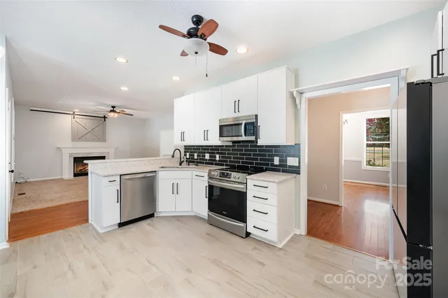 an empty room with wooden floor chandelier and windows