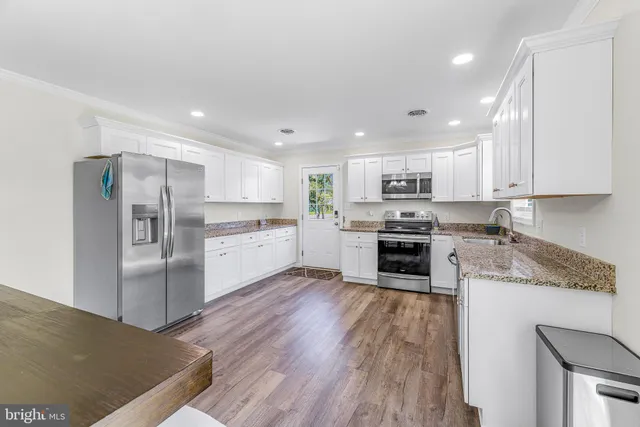 a kitchen with granite countertop a refrigerator oven a sink and cabinets