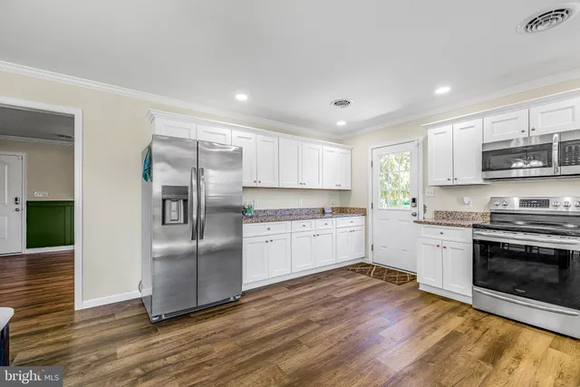 a kitchen with granite countertop a refrigerator and a stove top oven
