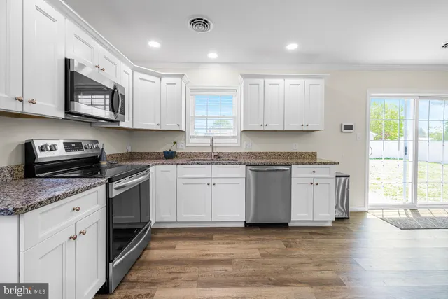 a kitchen with stainless steel appliances granite countertop a stove a sink and white cabinets