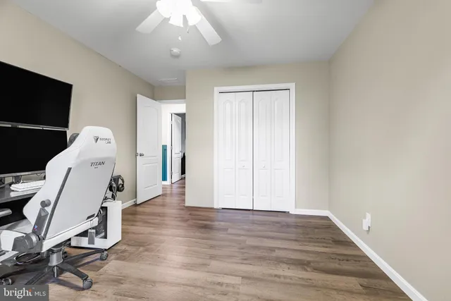 a view of a room with wooden floor and a ceiling fan