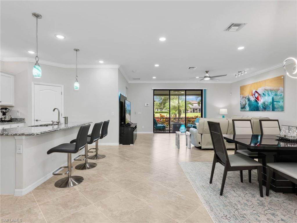 4383 Bismark Way Naples, FL 34119 - Photo 8 of 49 Kitchen, Dining Room, & Living Room with Track Lighting, & Sliders with Verticell Shade Leading to the Screened In Lanai with Lake View & Paver Lanai