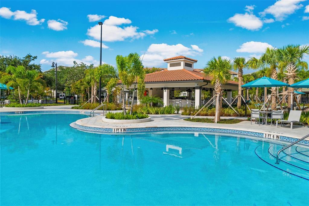 5025 Shoreway Loop, Unit 105 Orlando, FL 32819 - Photo 43 of 55 a view of a swimming pool with a lawn chairs under an umbrella