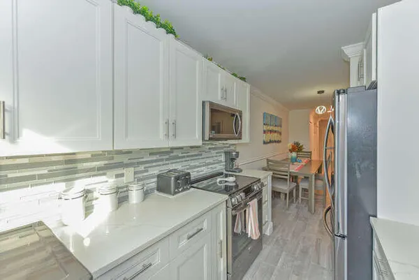 a kitchen with stainless steel appliances granite countertop a sink a stove a dining table and chairs
