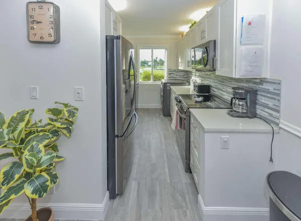 a kitchen with a refrigerator a stove a sink a counter space and a window