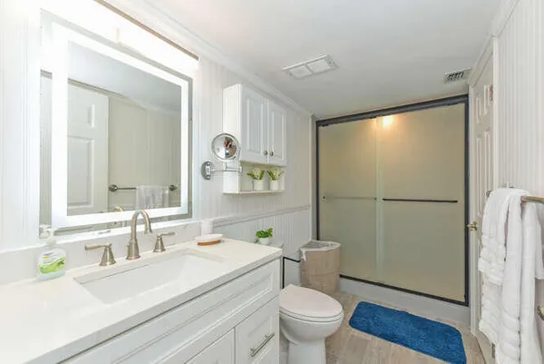 a bathroom with a sink a toilet a mirror and shower