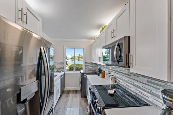a kitchen with stainless steel appliances a refrigerator a sink a stove and white cabinets