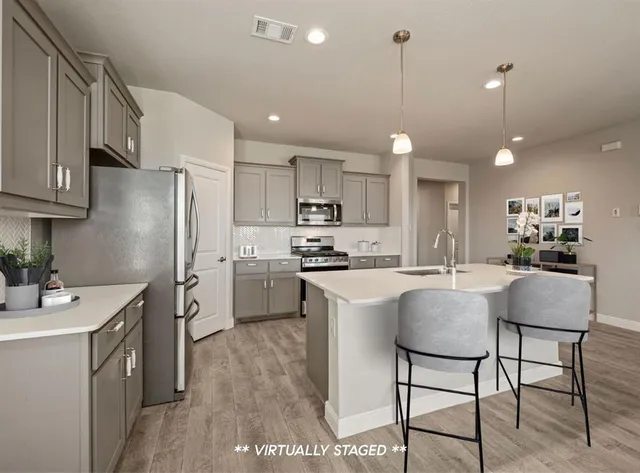 a kitchen with stainless steel appliances granite countertop a sink a stove a refrigerator cabinets and chairs