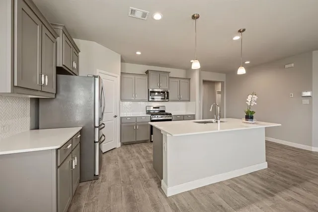 a kitchen with kitchen island a sink stainless steel appliances and wooden floor