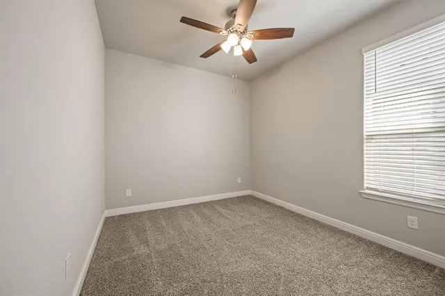 an empty room with a window and a fan