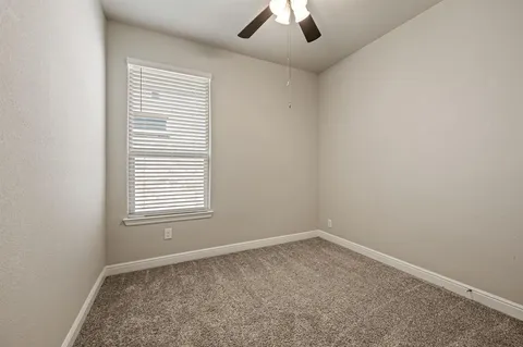 an empty room with a window and a ceiling fan