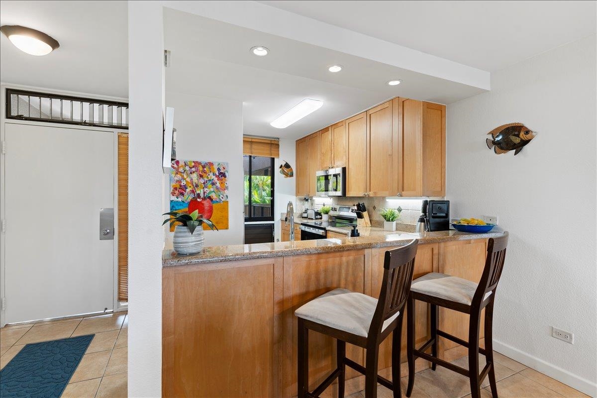2695 South Kihei Road, Unit 5205 Kihei, HI 96753 - Photo 10 of 43 a kitchen with stainless steel appliances granite countertop a dining table chairs and a refrigerator