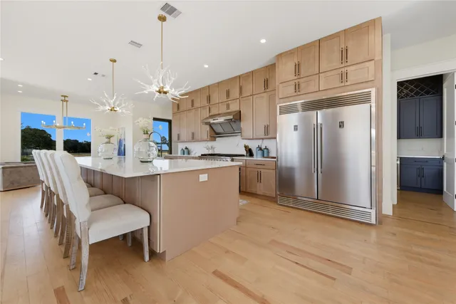 a kitchen with stainless steel appliances kitchen island granite countertop a refrigerator a stove a sink dishwasher with a dining table and chairs