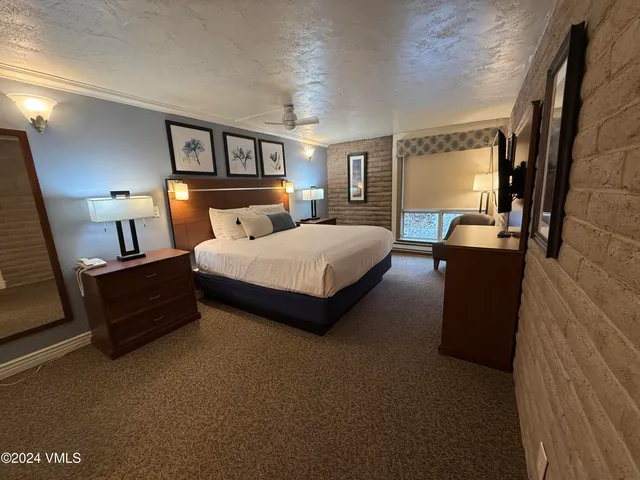 a bedroom with a bed lamp on desk and a window