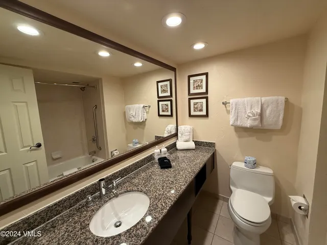 a bathroom with a granite countertop toilet a sink and mirror