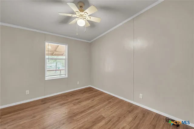 an empty room with wooden floor and fan