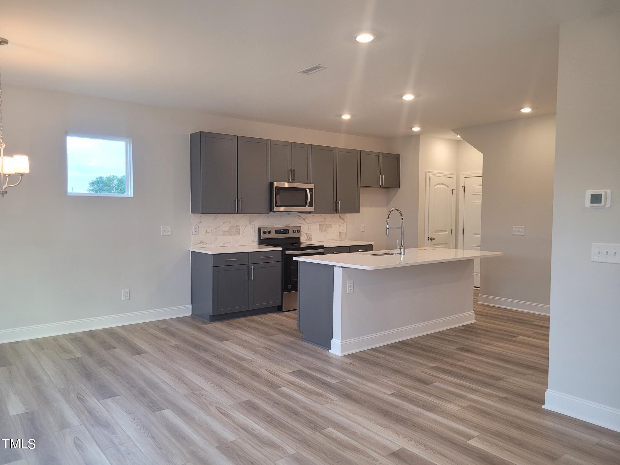 3611 Tarmac Road West Wilson, NC 27896 - Photo 13 of 28 a large kitchen with kitchen island a sink wooden floor and stainless steel appliances