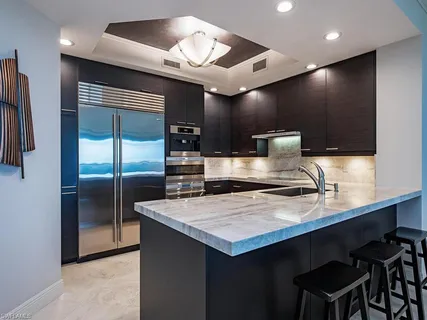 a large kitchen with a counter space a sink stainless steel appliances and cabinets