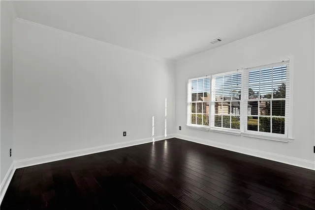 a view of an empty room with wooden floor fireplace and a window