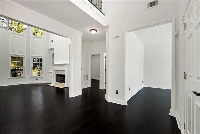 an empty room with wooden floor fireplace and windows