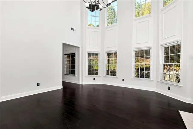 an empty room with wooden floor closet and windows