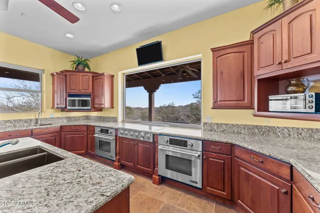 a kitchen with stainless steel appliances granite countertop a table chairs sink refrigerator and microwave