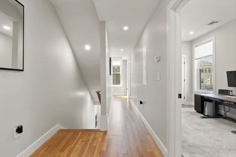 a view of a hallway with wooden floor and staircase