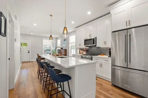 a kitchen with stainless steel appliances a refrigerator a stove a microwave oven a sink with island and chairs with wooden floor