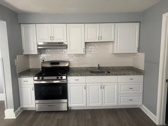 a kitchen with granite countertop white cabinets and stainless steel appliances