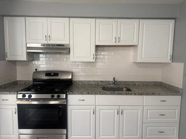 a kitchen with white cabinets and appliances