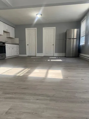 a view of empty room with wooden floor and window