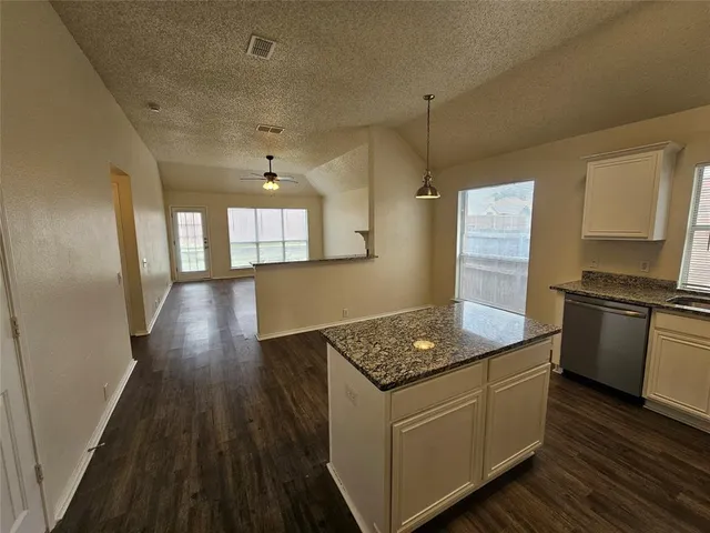 a kitchen with granite countertop a sink stove and refrigerator