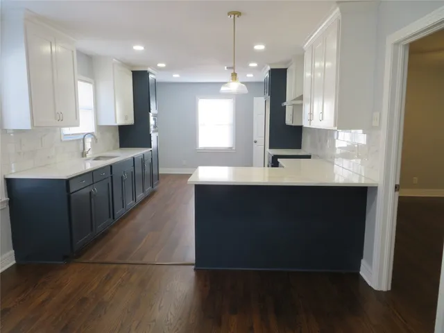 a large kitchen with kitchen island a sink dishwasher a refrigerator and a oven with wooden floor