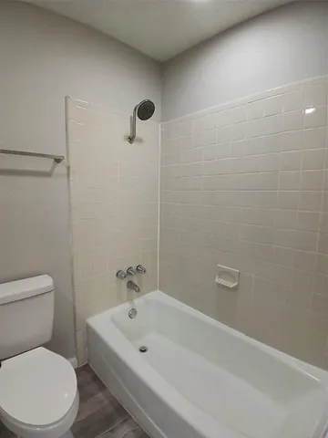 a white bath tub sitting next to a white toilet and a shower