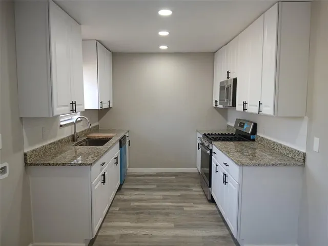 a kitchen with granite countertop a sink stove and cabinets
