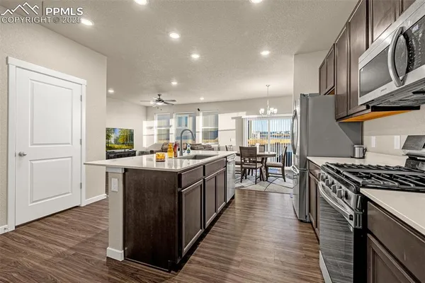 a kitchen with stainless steel appliances granite countertop wooden cabinets a sink a stove a window and a refrigerator