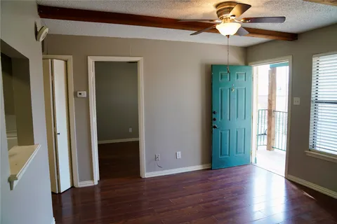 a view of an empty room with wooden floor and a window