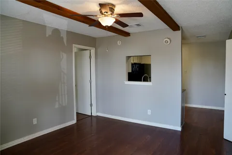 an empty room with wooden floor chandelier fan and windows