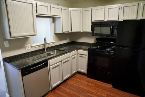 a kitchen with granite countertop white cabinets and black appliances