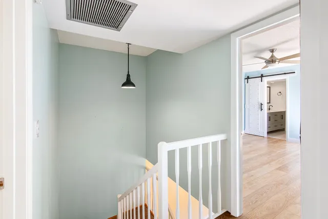 an empty room with wooden floor and a ceiling fan
