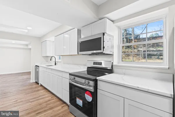 a view of an empty room with wooden floor and a fireplace