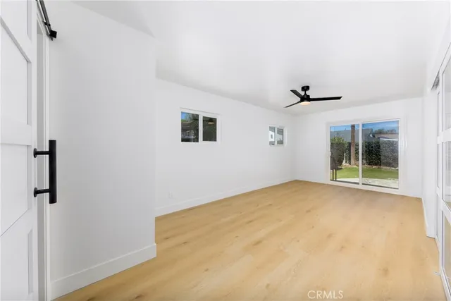 a view of empty room with wooden floor and ceiling fan