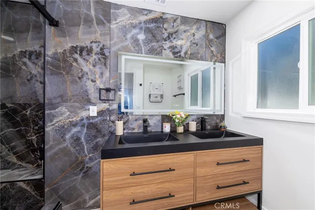 a bathroom with a granite countertop sink a mirror and shower
