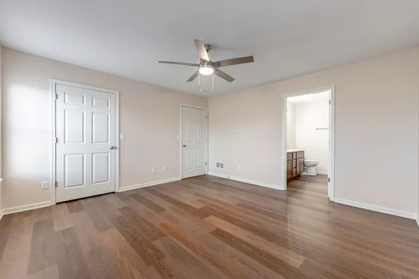 an empty room with wooden floor ceiling fan and windows
