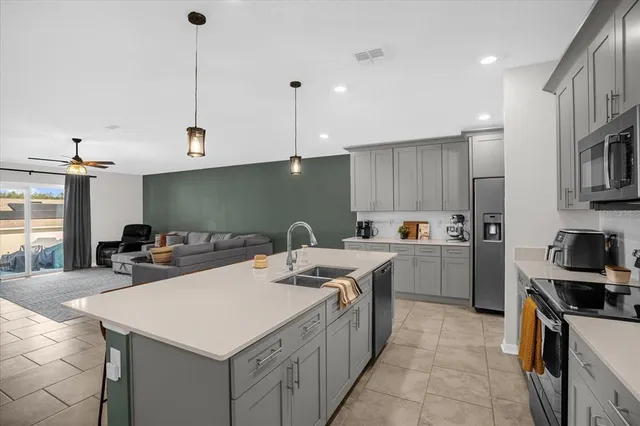 a kitchen that has a sink a microwave oven a stove and white cabinets with wooden floor