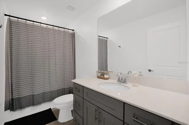 a bathroom with a sink a toilet a mirror and shower