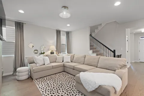 a large white kitchen with stainless steel appliances a stove a sink a refrigerator white cabinets and couches