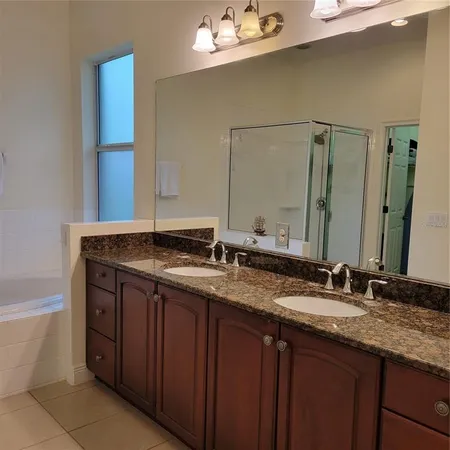 a bathroom with a granite countertop double vanity sink and a mirror
